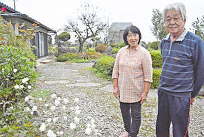 自宅の庭で談笑する小林さん夫婦
