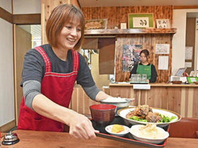 客席に定食を運ぶ富山さん。力の源は「お客さんの『おいしかったよ』という言葉」とほほ笑む（吉田義広撮影）