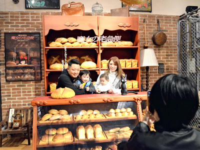 「ジブリ映画ポスタースタジオ」の「魔女の宅急便」のコーナーで記念撮影する来場家族。スタッフが撮影してくれるので、家族全員で写ることができる＝写真は秋田会場の様子（ ©Ｓｔｕｄｉｏ　Ｇｈｉｂｌｉ）