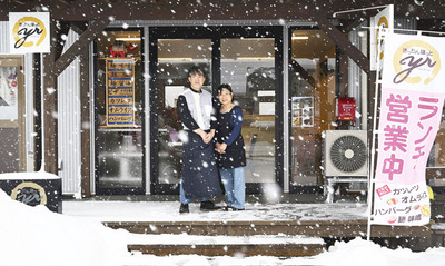 雪が降り積もる中、店頭に立つ六角保夫さん（左）と妻千賀子さん（矢内靖史撮影）