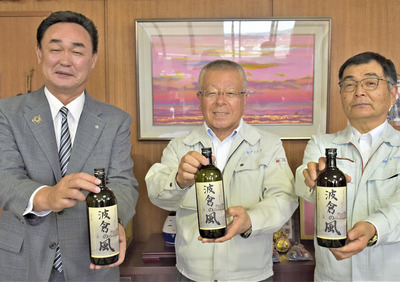 完成した芋焼酎「波倉の風」を手にする（左から）松本町長、渡辺社長、渡辺専務
