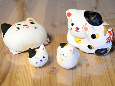 「うっかりネコ」シリーズの起き上がり小法師（右手前、１６５０円）、「にゃん頭」（左手前、１６５０円）、張り子（右奥、２７５０円）、お面（左奥、３８５０円）