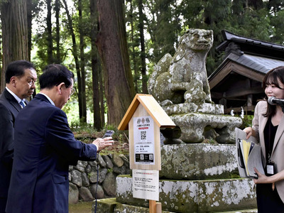 こま犬の前に設置されたＱＲコードを読み込む鈴木市長（右）ら