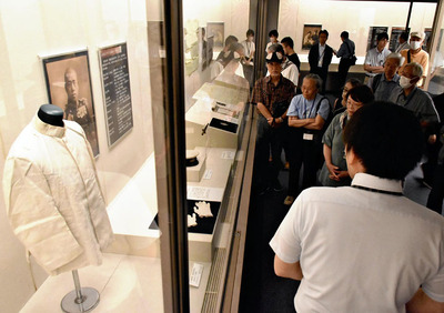 内覧会で資料に見入る参加者。会場には軍服など戦時中の資料約１５０点が並ぶ＝会津若松市・県立博物館