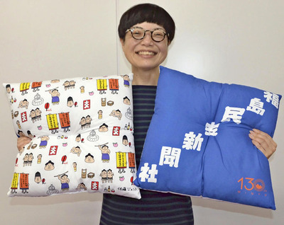 完成した座布団を手に笑顔を見せる佐藤さん