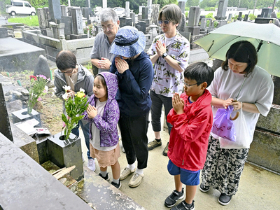 帰還困難区域の立ち入り規制が緩和された浪江町の墓地では、墓前に花を供えて手を合わせる家族連れの姿が見られた＝１２日午前、浪江町・井手唐沢墓地