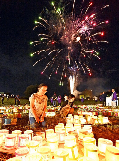 慰霊の明かりが灯籠にともされ、夜空を花火が彩った「福島とうろう流し花火大会」＝１７日午後、福島市・阿武隈川河畔