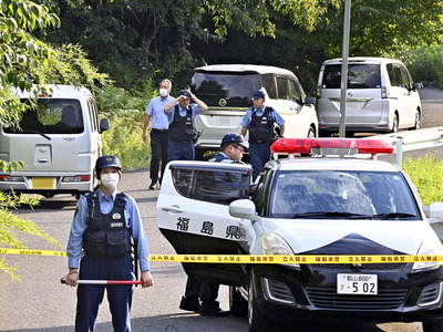 被害者宅に通じる道路付近を警戒する警察官＝２４日午後４時５０分、郡山市西田町
