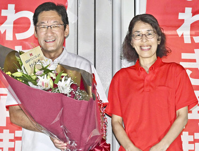 支援者から花束を受けて笑みを浮かべる内田さん（左）と妻葉子さん