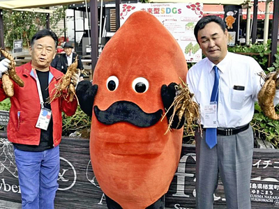 サツマイモを手にする永尾社長（左）と松本町長