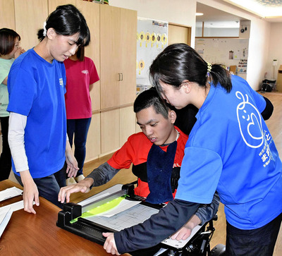 牛乳パックをカッターで切る利用者（右から２人目）