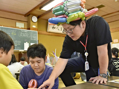子どもたちにバルーンアートを教える高島さん（右）