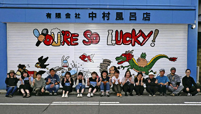 完成した一枚絵の前で笑顔を見せる関さんと中村風呂店の家族、おじさん活動研究所のメンバーら