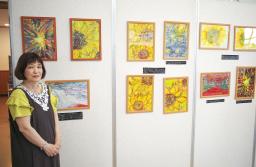 　平野義幸受刑者が刑務所内で描いた絵画の作品展と主催団体代表の青木恵子さん＝１６日午後、京都市