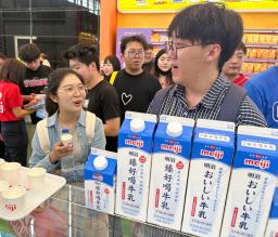 　明治のブースで「おいしい牛乳」を試飲する中国人来場者＝１９日、中国上海市（共同）