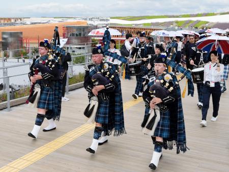 　英国のナショナルデーを迎え、バグパイプを演奏しながらパレードする軍楽隊＝２２日午前、大阪市此花区の夢洲