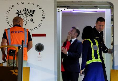 　２５日、ベトナム・ハノイに専用機で到着したフランスのマクロン大統領（中央奥）。妻ブリジットさんに手で顔を押されている（ロイター＝共同）