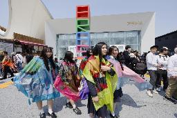 　ブラジル館（奥）で配られたマントを身に着けた来場者＝４月、大阪市此花区の夢洲