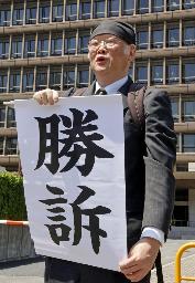 　「アベノマスク」の契約文書を巡る判決で、「勝訴」と書かれた紙を掲げる神戸学院大の上脇博之教授＝５日、大阪市北区
