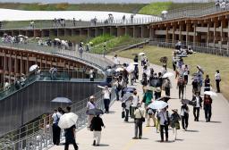 大阪・関西万博会場で、日傘を差して大屋根リングの上を歩く来場者=30日午後、大阪市此花区の夢洲