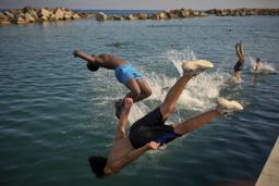 1日、スペイン北東部バルセロナで、水に飛び込む男性ら(AP=共同)