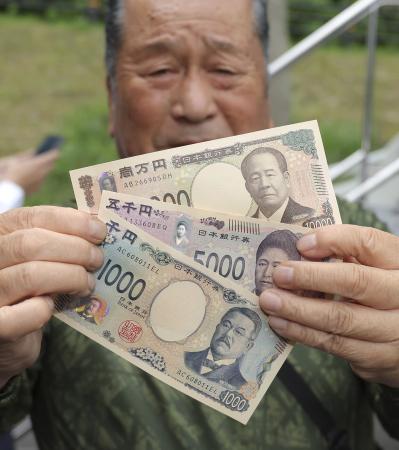 　新紙幣を手にする人＝２０２４年７月、熊本県小国町