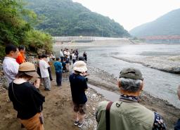 2020年7月の豪雨から5年となり、氾濫で多くの被害をもたらした球磨川(奥)周辺で黙とうする人たち=4日午前、熊本県八代市
