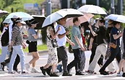 真夏のような強い日差しの下、日傘を差す人たち=6月28日、東京都千代田区