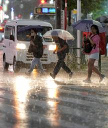 大雨の中、傘を差して歩く人たち。前線などの影響で関東甲信と東北地方で大気の状態が非常に不安定になった=10日夕、東京・池袋