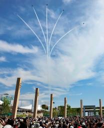 　薄雲がかかった大阪・関西万博会場の上空を展示飛行する航空自衛隊のアクロバットチーム「ブルーインパルス」。大勢の来場者が妙技を見守り大きな歓声や拍手が沸いた＝１２日午後、大阪市此花区の夢洲