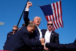昨年7月、選挙集会で銃撃を受け、大統領警護隊に囲まれながら拳を上げるトランプ氏=米ペンシルベニア州バトラー(AP=共同)