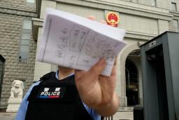スパイ罪で起訴された日本人男性の判決公判が開かれた北京市の第2中級人民法院前で撮影を阻止する警察官=16日(共同)