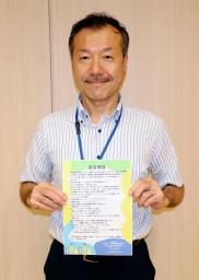 　脱炭素に向けた企業宣言制度のチラシを持つ東京都千代田区の川又孝太郎ゼロカーボン推進技監＝６月、東京都千代田区