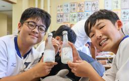 　オリジナルラベルが貼られたボトルを手に、笑顔を見せる兵庫・淡路島の私立蒼開中の生徒＝３０日午後、高知県室戸市
