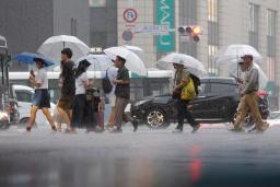 　強い雨が降る中、傘を差して歩く人たち＝１０日午後、福岡市