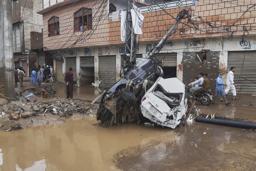 豪雨による洪水で流され、電柱に衝突した車=15日、パキスタン北西部ミンゴラ近郊(AP=共同)