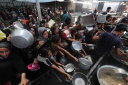 ガザ中部ヌセイラト難民キャンプで、配給の食べ物を受け取ろうとする人たち=16日(ゲッティ=共同)