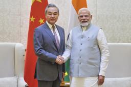 19日、ニューデリーで握手するインドのモディ首相(右)と中国の王毅外相(インド首相府提供・AP=共同)