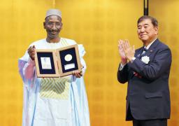 第5回野口英世アフリカ賞の授賞式で、石破首相(右)から拍手を送られるマリのアブドゥライ・ジムデ博士=22日夕、東京都港区の明治記念館(代表撮影)