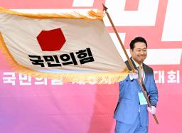 韓国の保守系最大野党「国民の力」の新代表に選出され、党の旗を掲げる張東赫国会議員=26日、ソウル(共同)