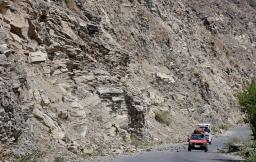 アフガニスタン東部クナール州ヌールガルで、落石を避けて通る車=5日(共同)