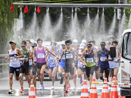 北海道マラソンで、ミストシャワーをくぐるランナー=8月、札幌市