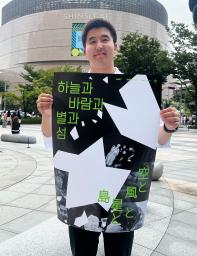 映画「空と風と星と島」のポスターを手にする金明允さん=19日、韓国・釜山(共同)