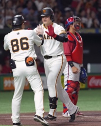 　２回、先制ソロを放ちコーチとタッチを交わす巨人・岡本。広島の捕手石原＝東京ドーム
