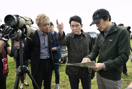 　説明を聞きながら釧路湿原周辺にある大規模太陽光発電所の建設予定地を視察するアルピニストの野口健さん（中央）＝２日午前、北海道釧路市