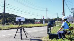 　事故現場付近で速度違反車を監視する警察官＝９日午前、三重県名張市