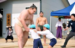　園児と相撲を取る安青錦。奥は今年完成した屋内の稽古場＝３０日、福岡県久留米市