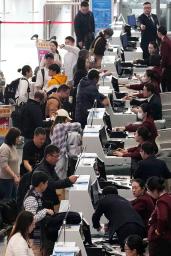 　北京首都空港の日本便などを扱うカウンターで搭乗手続きをする人たち＝１５日（共同）