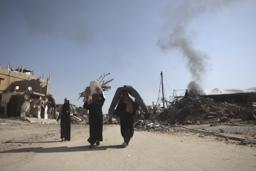 　ガザ南部ハンユニスで破壊された自宅から回収した衣類や毛布を運ぶパレスチナ人＝１８日（ゲッティ＝共同）