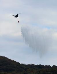 　大分市佐賀関の大規模火災現場付近で上空から散水する自衛隊のヘリコプター＝２０日午前１０時２６分